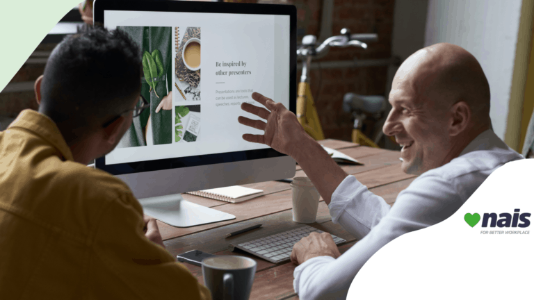 two men talking and smiling in front of a computer