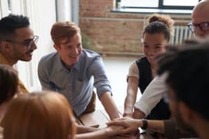 Group of employees holding hands and supporting each other smiling and being inclusive