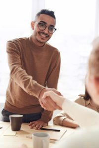 Man smiling and holding out a hand shake